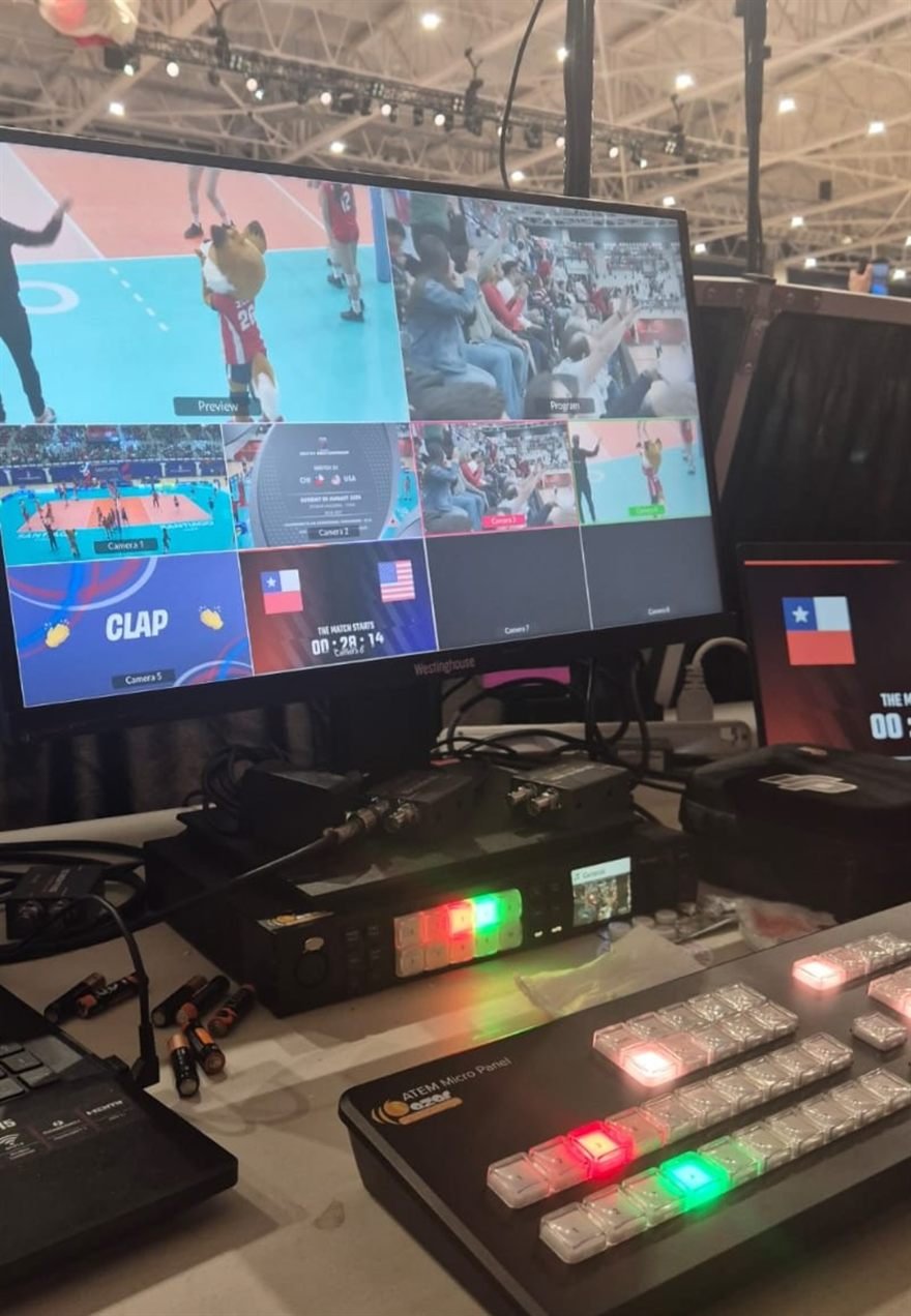 Panel de control con botones iluminados y monitor multiview durante una transmisión deportiva.